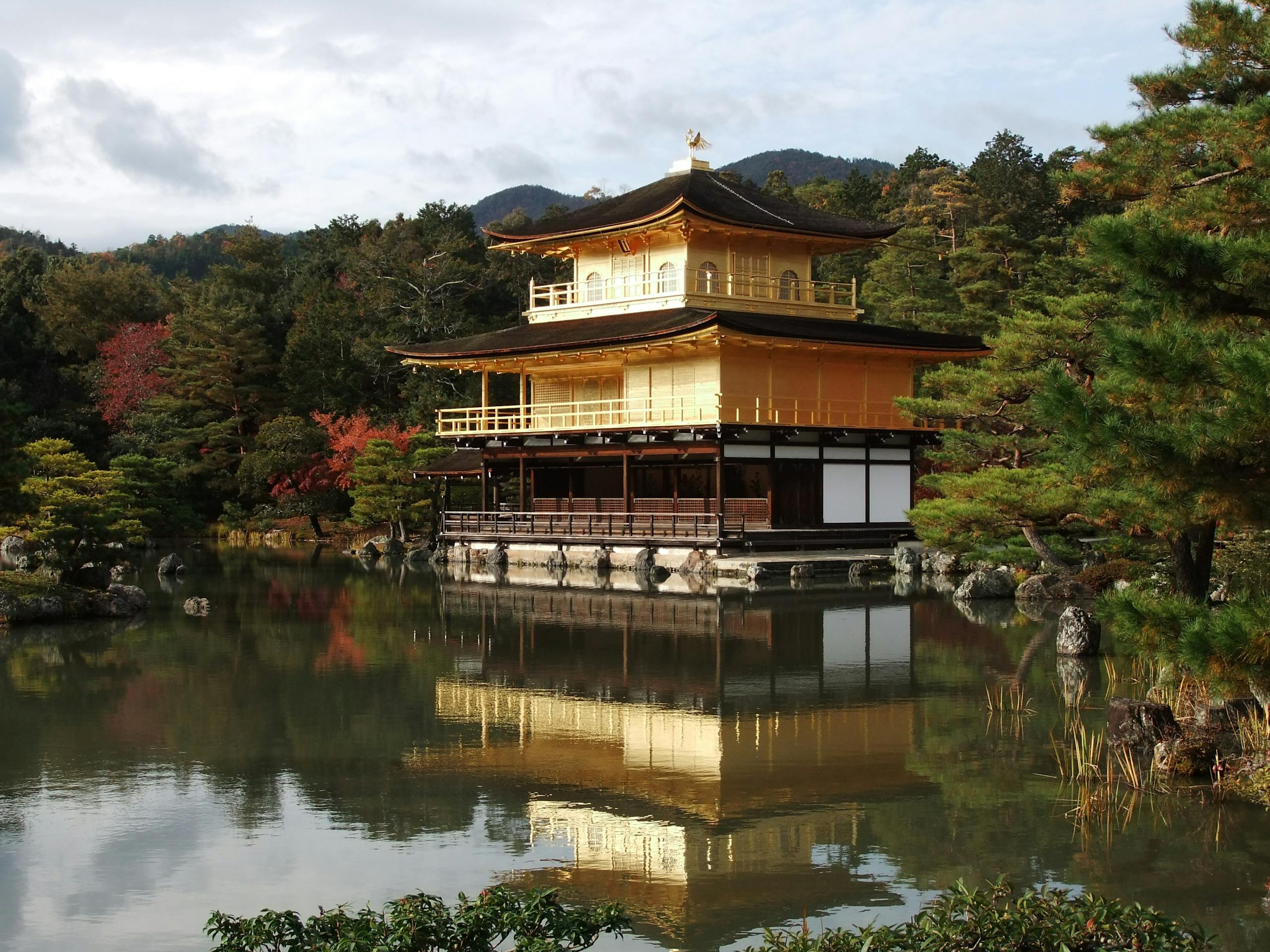 Golden Pavilion reflecting in a serene pond surrounded by lush greenery, Kyoto, Japan.